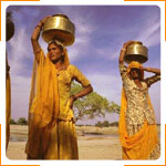 Rajasthan, three tribeswomen collecting water in brass jars